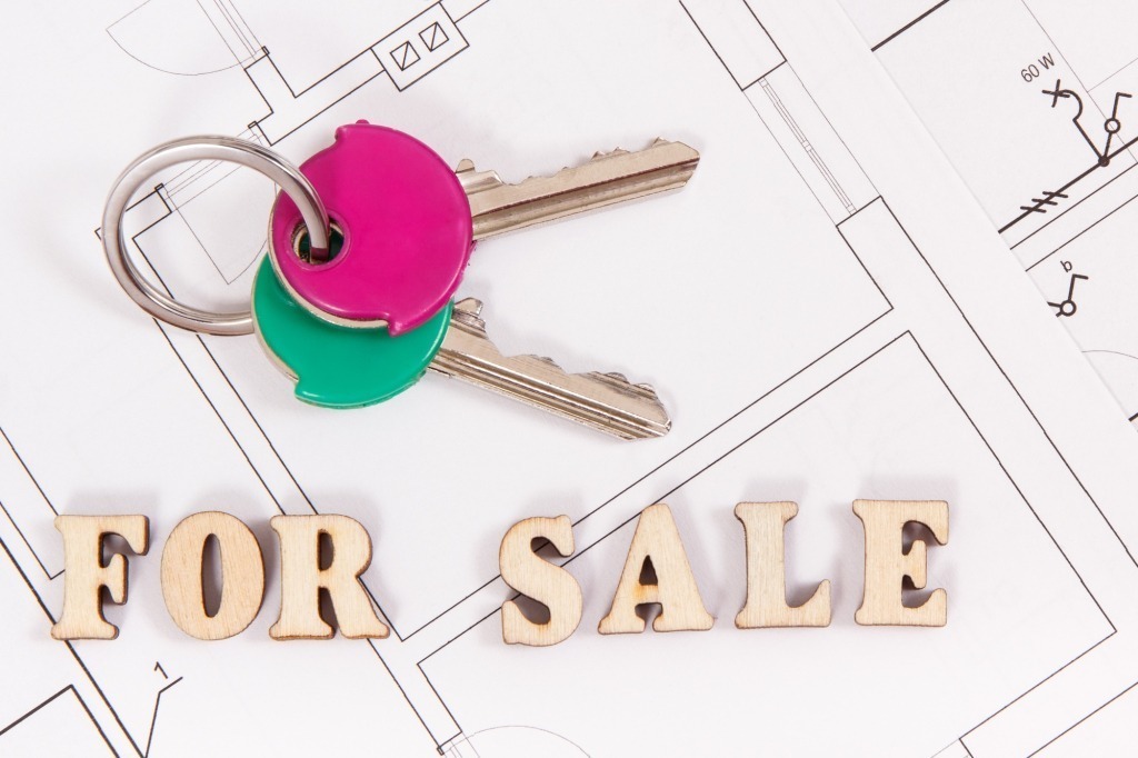 Home keys with inscription for sale on housing plan, concept of selling or buying house