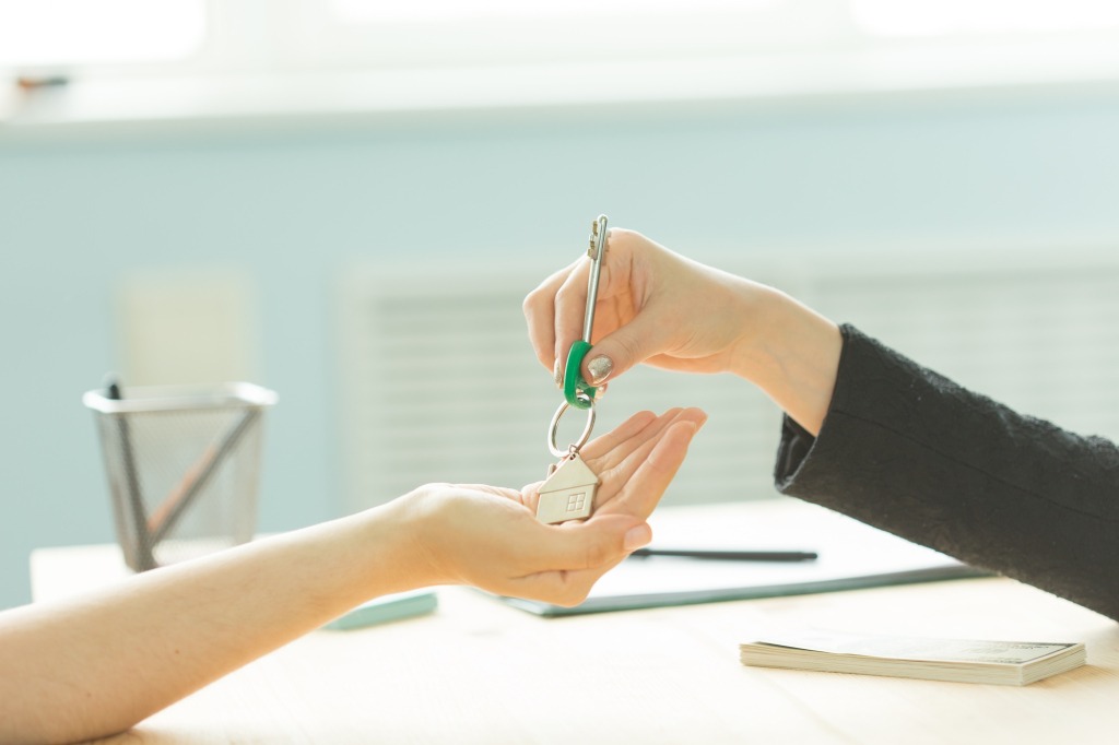 Business, realtor and real estate concept - Hand-to-hand key from new home